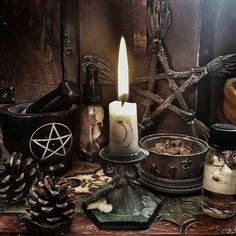 a table topped with lots of different types of items next to a candle and some pine cones