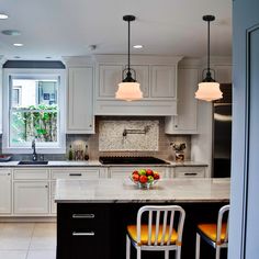 a kitchen with white cabinets and yellow chairs