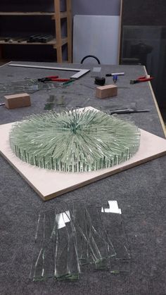 a table topped with lots of glass pieces on top of a gray floor covered in plastic