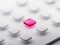 a pink diamond sitting on top of a white surface surrounded by smaller square objects in the background