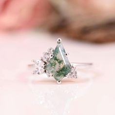 a close up view of a ring with a green stone and white diamonds on it