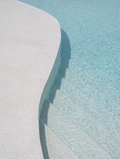 a skateboard is sitting on the edge of an empty swimming pool with blue water