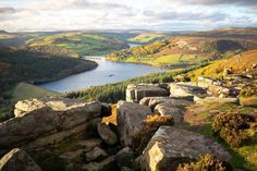 the view from high up on some rocks in the hills near water and trees with yellow leaves