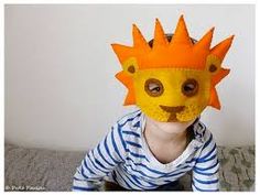 a young child wearing a paper crown on top of his head, sitting on a bed