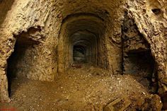 an underground tunnel with rocks and dirt on both sides, leading into the distance to another cave