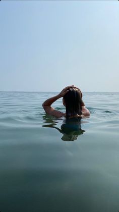 a woman is floating in the water with her head on her hands while looking at the sky