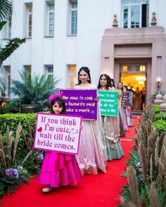 some girls are holding signs on a red carpet