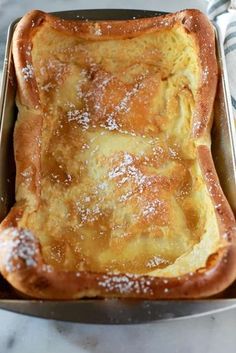 a pan filled with bread covered in powdered sugar on top of a marble counter