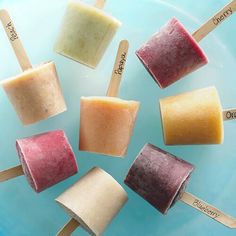 several popsicles are arranged on a blue plate with wooden stick labels that say different flavors