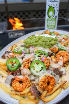 a plate full of french fries with shrimp and guacamole on the side