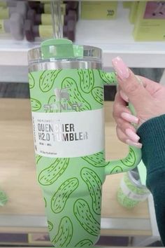 a person holding up a green tumbler cup with cactus designs on it in a store