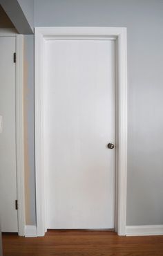 an open door in a room with hard wood flooring and white paint on the walls