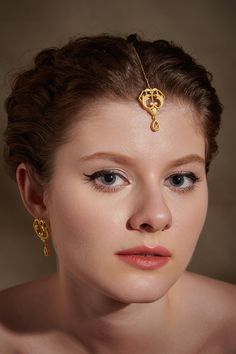 Inspired from the Rococo Era, the tikka headpiece features intricate floral patterns. It is handcrafted using ancient filigree and embossing techniques finished in 18K matt gold plating. The ornate motifs add to the uniqueness and grandeur of the piece. The tikka is perfectly suited to match with traditional outfits. Whether it's a sangeet or a cocktail, style with desi, fusion and contemporary looks. Pair it with matching earrings and choker to complete the occasion look. Chain Length: 10 cm Mo Elegant Tikka With Intricate Design For Navratri, Elegant Ceremonial Tikka For Navratri, Elegant Ceremonial Tikka For Diwali, Elegant Tikka For Navratri, Elegant Ceremonial Tikka With Tilla Detailing, Elegant Ceremonial Tikka With Intricate Design, Ceremonial Elegant Cutdana Tikka, Traditional Adjustable Tikka For Ceremonial Occasions, Elegant Ceremonial Tikka