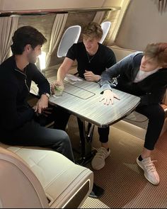 three people sitting at a table in an airplane