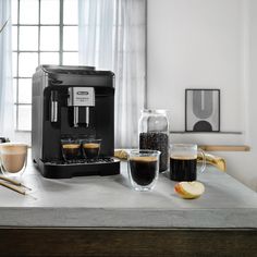 an espresso machine sitting on top of a counter next to two glasses of coffee