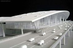 a model of a white building with lots of cars on the road in front of it