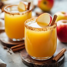 two glasses filled with an apple cider and cinnamon stick garnished with sugar