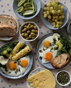 an assortment of food on plates with bread, grapes, and other foodstuffs