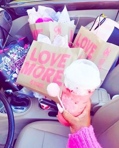 a person in a car holding up some paper bags with the words love more on them