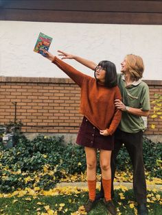 two people are standing in front of a building and one is pointing at the book