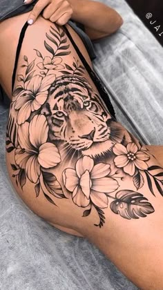 a woman's thigh with a tiger and flowers tattoo on it