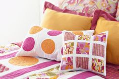 a bed topped with lots of colorful pillows