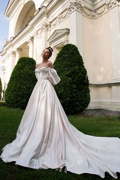 a woman in a white wedding dress standing on the grass