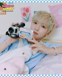 a person laying on a bed with a camera and stuffed animal in front of them