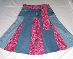 a pink and blue skirt is laying on a white bed sheet with the bottom half rolled up