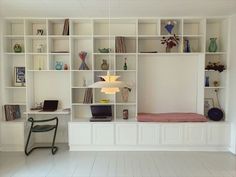 a room with white shelves filled with books and vases