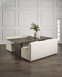 a table with two chairs and a vase on top of it in front of a white wall