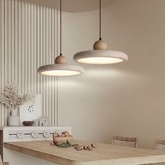 three lights hanging from the ceiling above a kitchen table with chairs and a stove in front of it