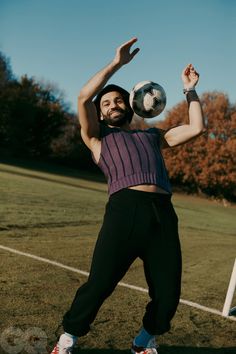 a man holding a soccer ball on top of his head while standing in the grass