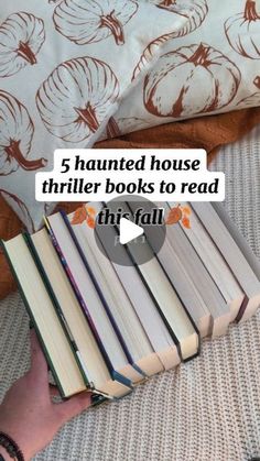 a person holding a stack of books with the title 5 haunted house thrifter books to read this fall