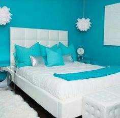 a bedroom with blue walls and white bedding in the center, along with fluffy rugs on the floor