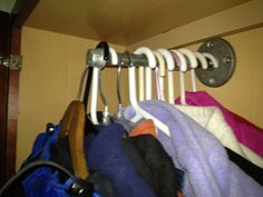 a rack with clothes hanging on it in front of a wooden door and some metal hooks