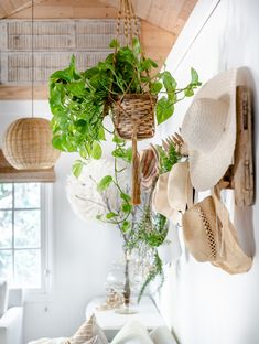 several hats hanging from the ceiling in a room with white walls and wooden beams,