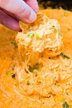 a person scooping some food out of a pot filled with cheesy potatoes