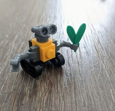 a toy robot holding a green leaf on top of a wooden table