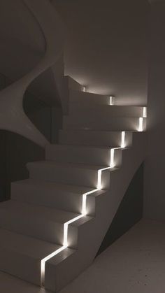 an illuminated staircase in a dark room with white walls and flooring is lit by bright lights