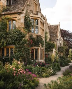 an old house with lots of flowers growing on it