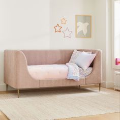 a pink couch sitting on top of a wooden floor next to a white rug in a living room