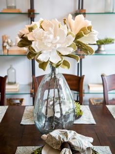 a vase filled with white flowers sitting on top of a table next to a napkin