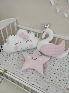 two pillows that are on top of a crib next to a stuffed swan and star