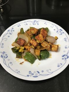 a white plate topped with tofu and veggies on top of a table