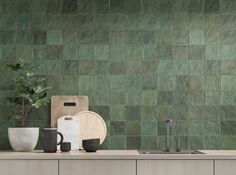 a kitchen with green tiles on the wall and counter tops, including two mugs