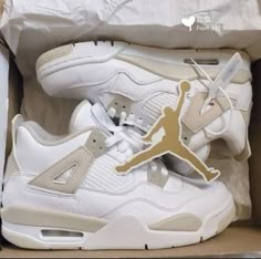 a pair of white and gold air jordans in a box with paper cutouts