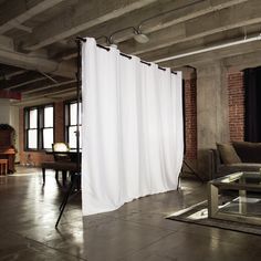 an empty room with a white curtain in the center and a couch on the other side