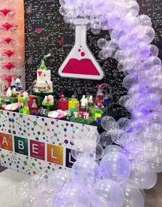 an assortment of balloons and cake on display at a party or event in front of a blackboard wall