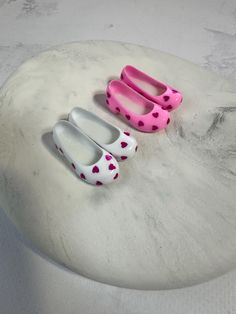 two pairs of pink and white shoes sitting on top of a marble table next to each other